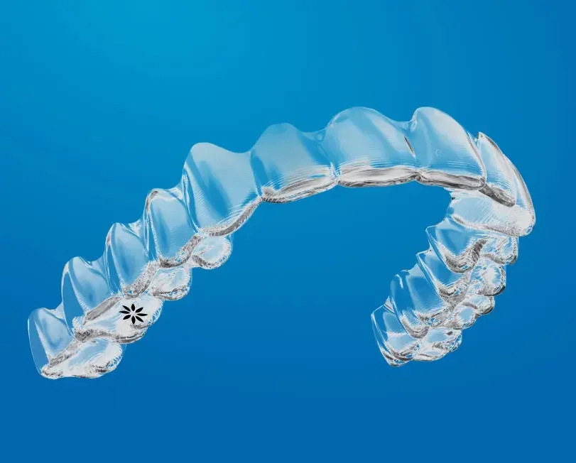 Close-up of a transparent Invisalign aligner tray against a blue background.