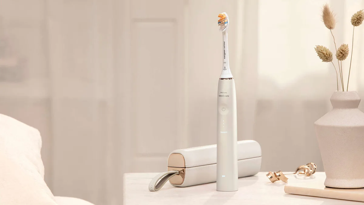 Philips Sonicare 9900 Prestige electric toothbrush beside its matching travel case on a bathroom counter.