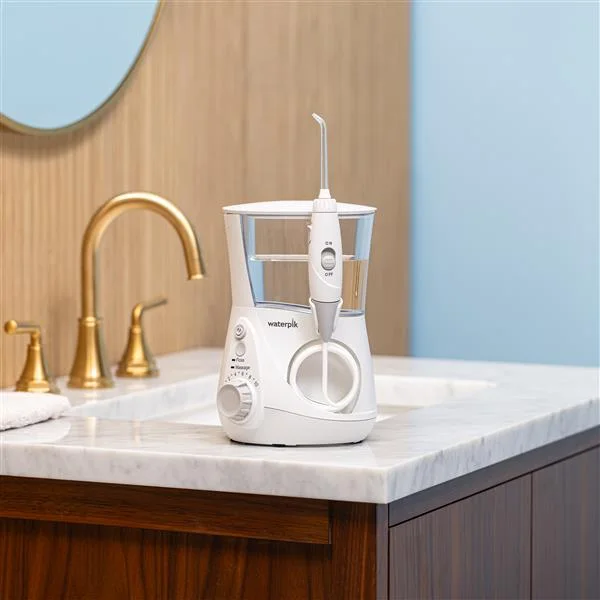 White Waterpik Aquarius WP-660 water flosser on a bathroom counter beside a sink.