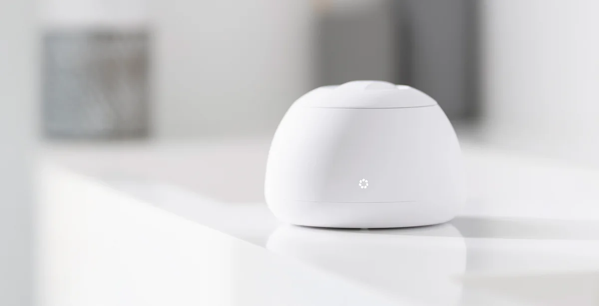 A white Zima Dental Pod with its lid closed, sitting on a bathroom counter beside a sink.